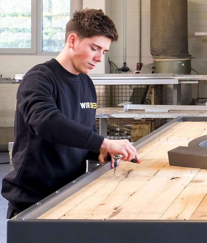 Junger Mitarbeiter von WIR DREI in einer Werkstatt bei Gebrauch von nachhaltigen Werkstoffen.