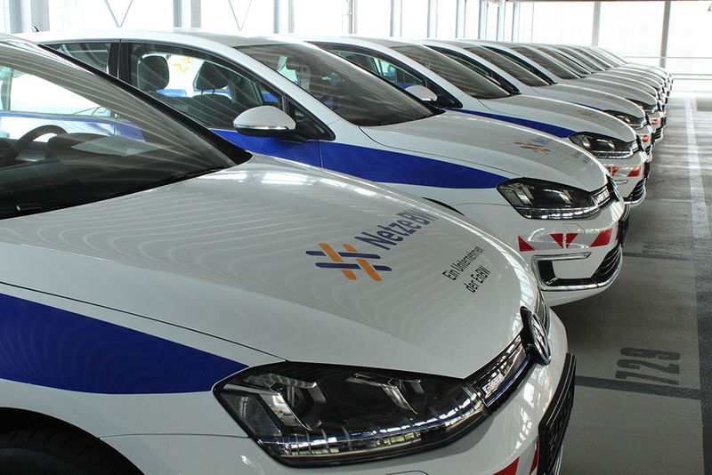 Es sind viele hintereinanderweg stehende VW-Polos in einem Parkhaus mit einheitlichem Brand-Design abgebildet.