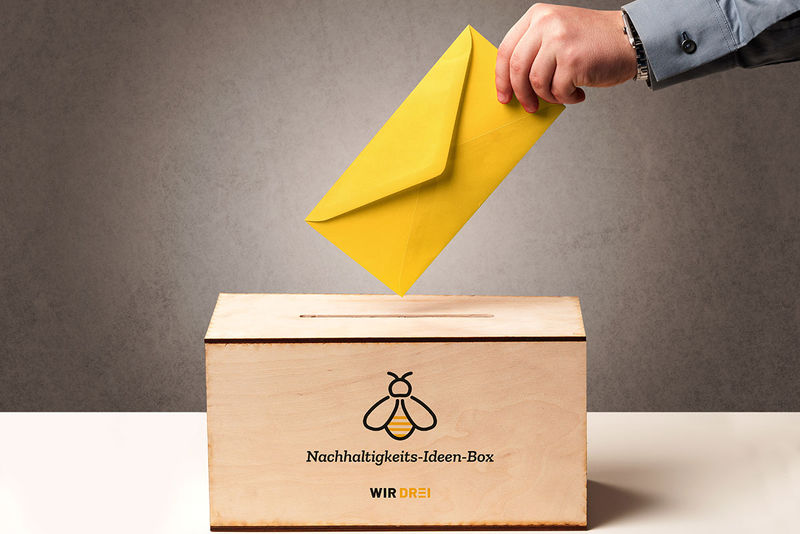 Ideenbox aus Holz in die ein Gelber Brief eingesteckt wird.