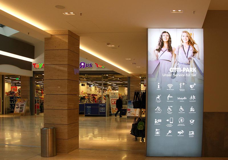 Strahlkräftiges, leuchttransparentes und mit Icons bestücktes Citti Park Schild in einem Einkaufszentrum.