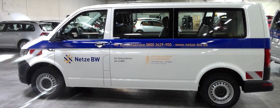 Ein VW-Bus der EnBW-Fahrzeugflotte in einem Parkhaus mit einem Kontaktformular und dem Netze BW Logo beschriftet.