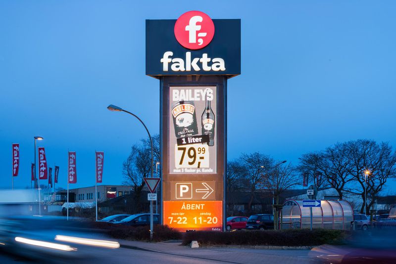 Digita Signage mit einem großen "fakta" Logo Schild, Baileys Werbung und Parkplatzhinweis.