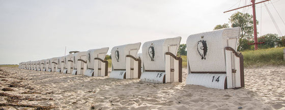 Vier speziallackierte Strandkörbe am Strand.
