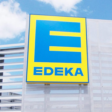 Hoch angebrachtes, leuchttransparentes EDEKA Logo Schild.